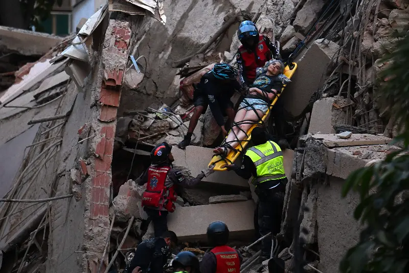 Rescue workers carry a person on a stretcher out of a collapsed building following an earthquake in Caracas on June 24, 2026. A magnitude 7.1 earthquake struck Venezuela on Wednesday, the United States Geological Survey (USGS) reported, triggering panic in Caracas, according to AFP journalists. The tremor, which was followed by several aftershocks, was also felt in Colombia. (Photo by Juan BARRETO / AFP)