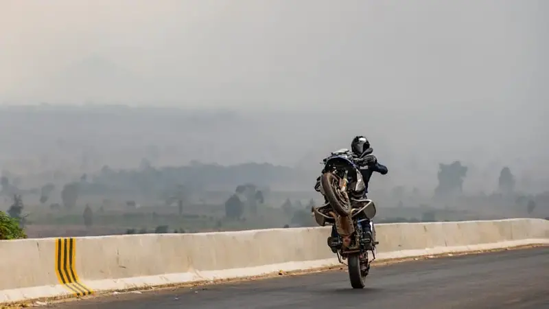 Man performing wheelie on heavy adventure bike in Cambodia