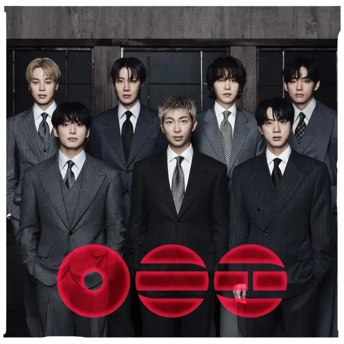 BTS dressed in stylish suits, standing in two rows against a dark background with a modern design. The front row features four men, while the back row includes four more, with various expressions and hairstyles.