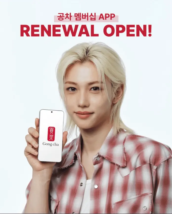 A person with light hair wearing a plaid shirt holds a smartphone displaying the Gong cha logo, promoting the app renewal with the text 'RENEWAL OPEN!' in bold lettering.