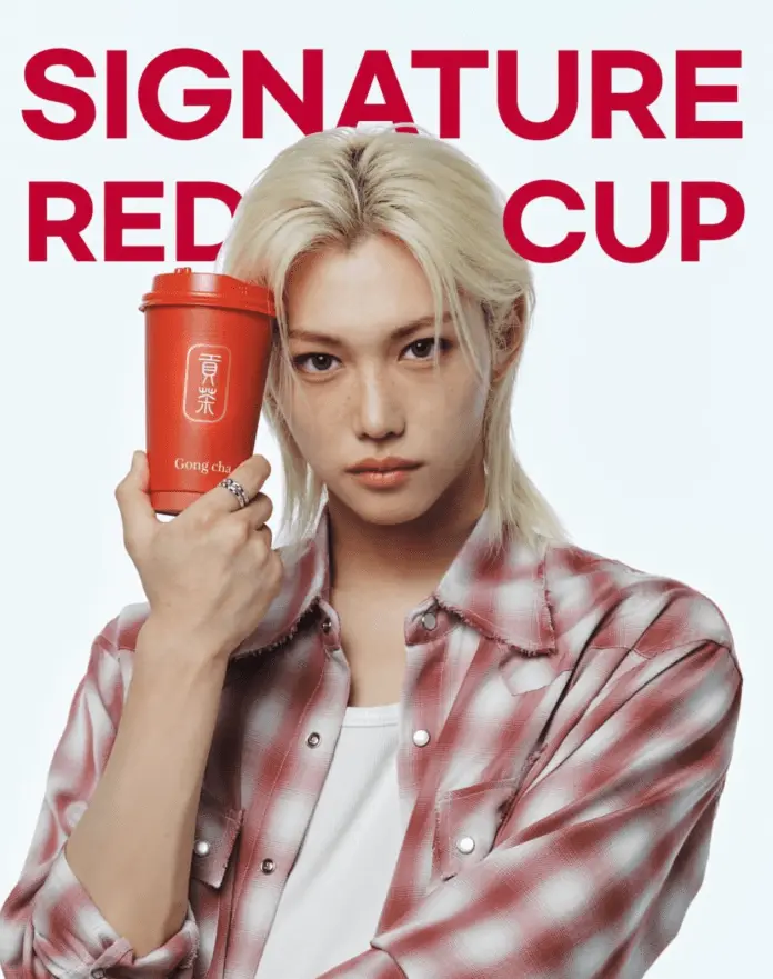 A person with long blonde hair holds a red cup, wearing a checkered shirt against a plain background with the text 'SIGNATURE RED CUP' in bold.