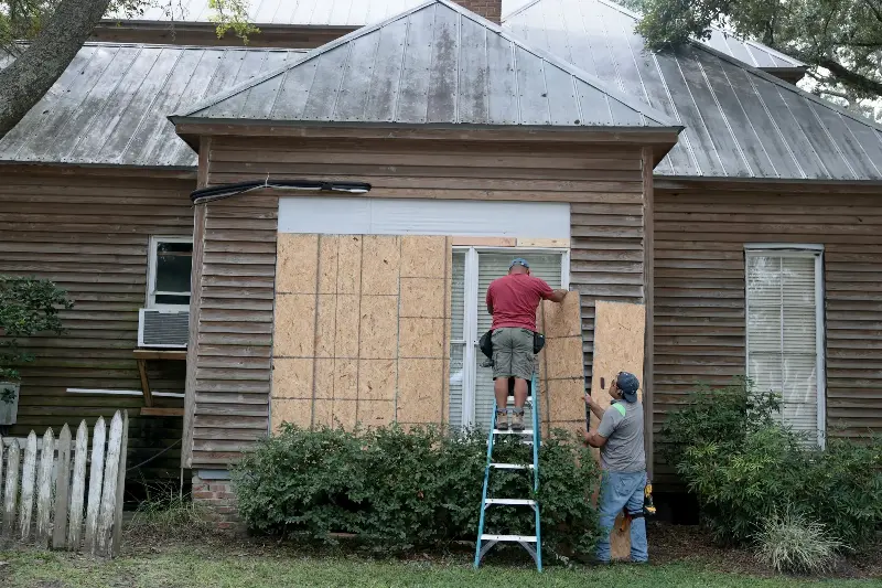 Aaron Chi and Wilner Garcia place plywood over the windows of a home as they prepare for the possible arrival of Hurricane Isaias on October 8, 2026 in Pensacola, Florida.
