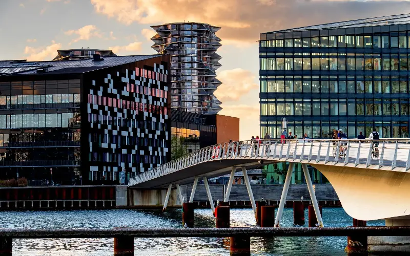 People walking the modern steel Bryggebroen bridge at sunset in Copenhagen, Vesterbro district, Denmark, street life in Scandinavia.