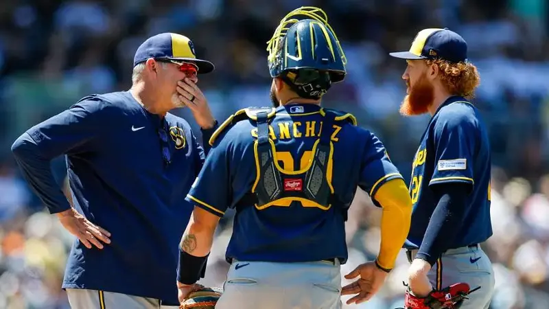 Milwaukee Brewers pitching coach Chris Hook (84) talks with starting pitcher Dustin May