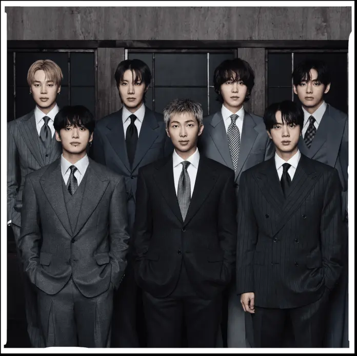 A group of seven men dressed in formal suits standing together against a dark background, posing for a photograph.