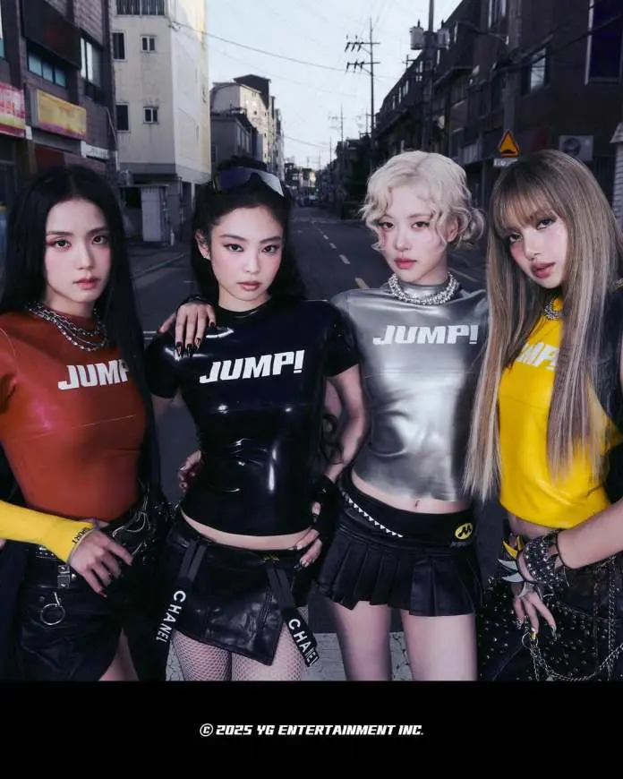 BLACKPINK memebrs posing together in a street, all wearing matching outfits with the word 'JUMP!' displayed prominently. The women exhibit a stylish and edgy fashion sense, with black, red, silver, and yellow tops and skirts. The street setting features buildings and a clear sky in the background.