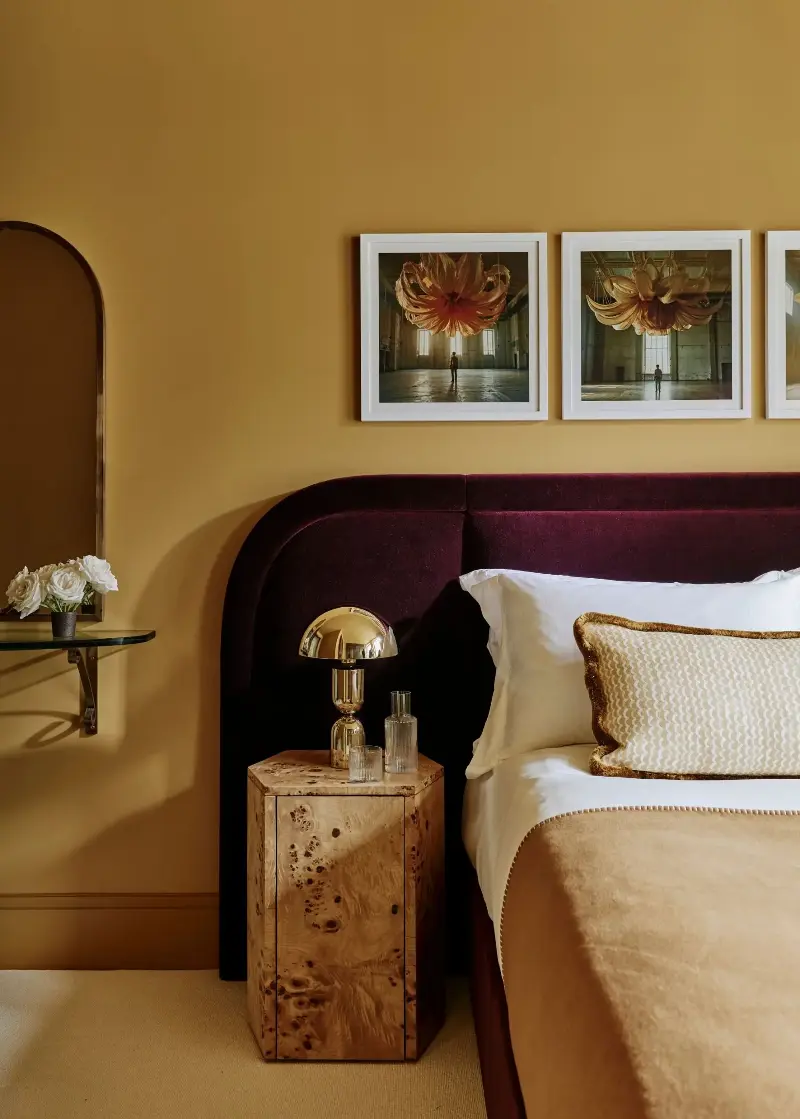 Farrow & Ball's India Yellow brings a sense of warmth and coziness to this bedroom, while the rich burgundy furnishings add depth.   (Image credit: Christopher Horwood. Design: Studio Squire )