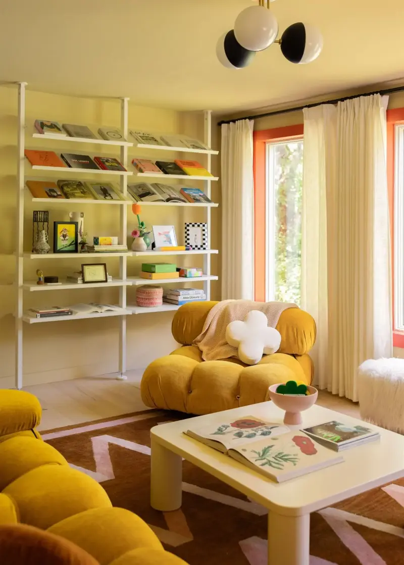 The butter yellow walls in this living room were painted with Farrow & Ball's Hay, along with Backdrop's Bada Bing! on the window trim, a similar shade to Benjamin Moore's Salsa.  (Image credit: Olivia Nadel. Design: Daniela Araya)