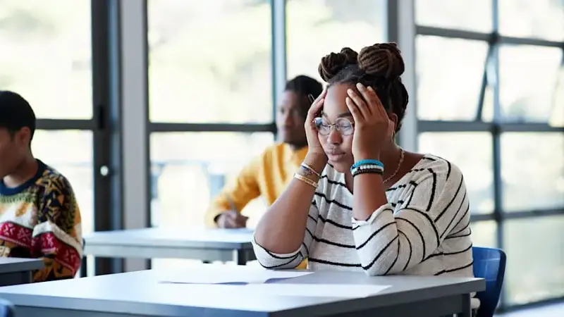 Worried student sitting with head in hands at desk