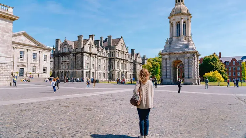 A woman standing with a backpack in the courtyard of Trinity College in Dublin, Ireland.