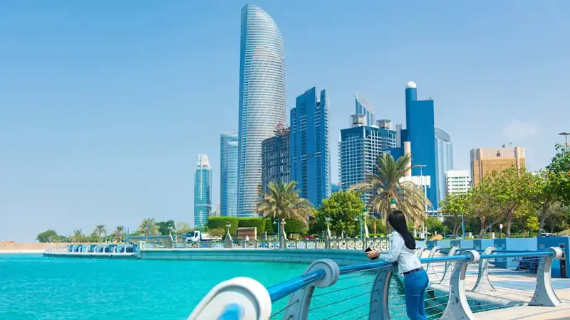 Female tourist visiting Abu Dhabi downtown corniche area and enjoying the view
