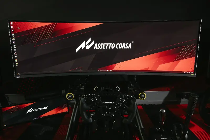 Assetto Corsa EVO on an ultrawide MSI monitor with a Fanatec racing wheel in the foreground
