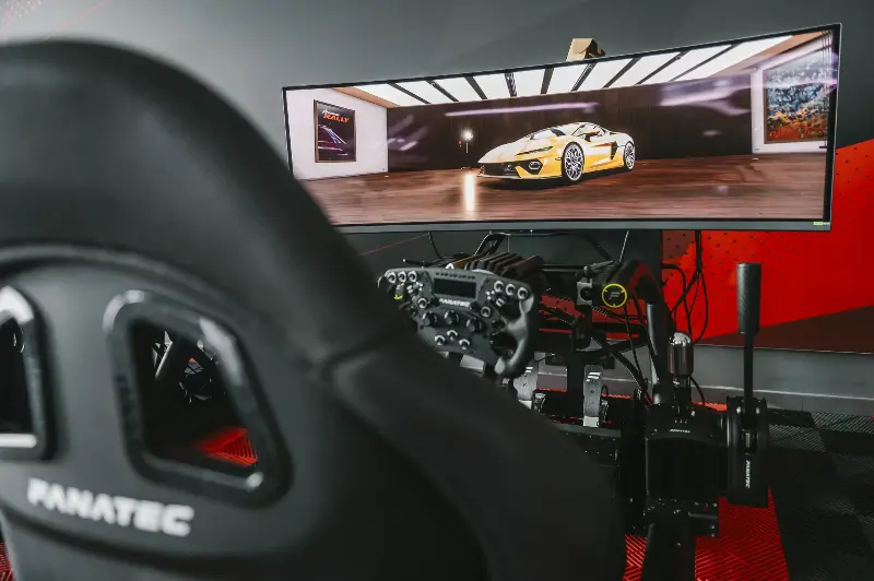 Racing simulator cockpit with Assetto Corsa EVO gameplay on ultrawide monitor