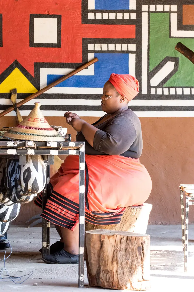 A craftswoman at Lesedi Cultural Village in South Africa uses traditional hand skills, an example of the knowledge and livelihoods Safia Minney believes fashion’s just transition must value and protect (Getty)