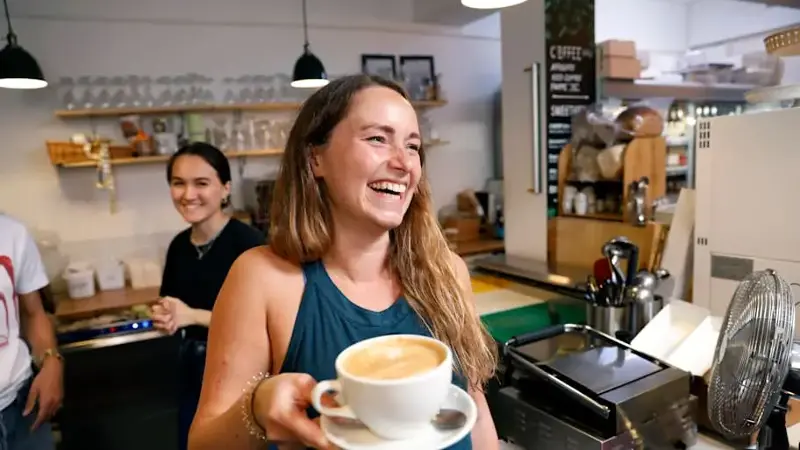 A smiling waitress serving a coffee