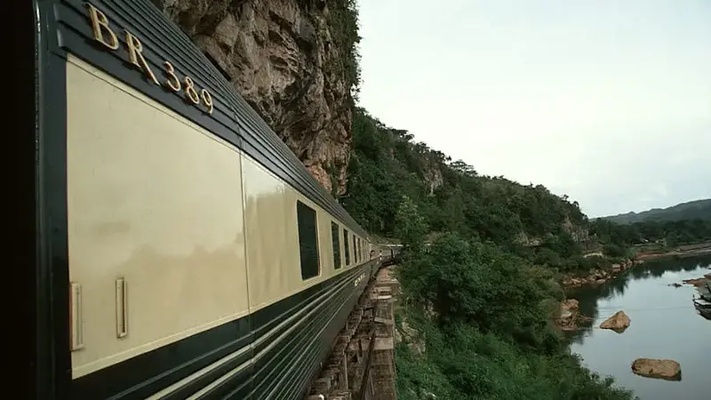 The Eastern and Oriental Express train crosses a wood-tresseled bridge.