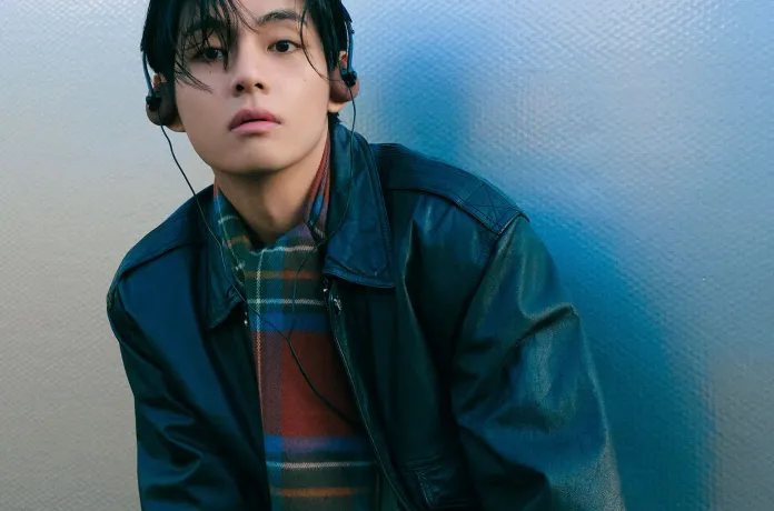 V wearing a black leather jacket and colorful striped scarf, listening to headphones against a textured blue background.