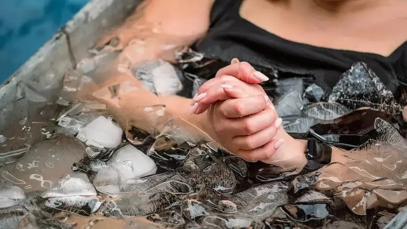 Woman sitting in bathtub full of ice