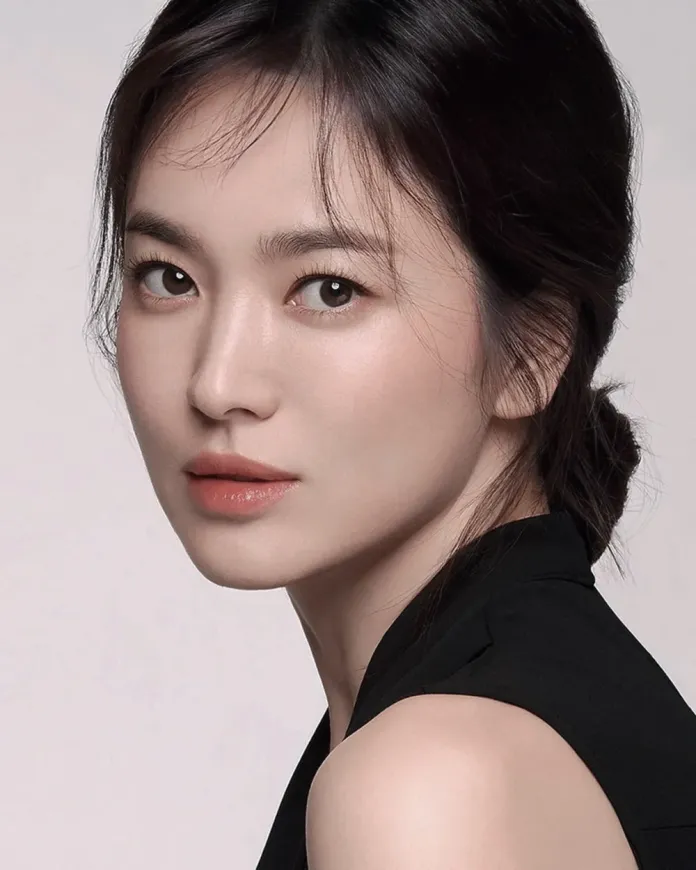 A close-up portrait of Song Hye-Kyo with long dark hair, wearing a black sleeveless top, looking directly at the camera with a soft expression.