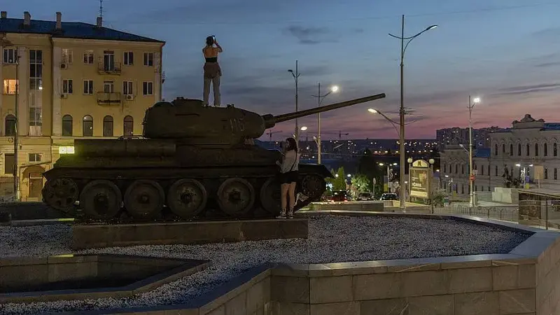 A woman photographs Kharkiv, Ukraine, from atop a Soviet-era T-34-85 tank.