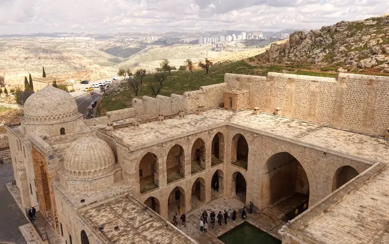 أُعيد افتتاح المدرسة القاسمية التاريخية في مدينة ماردين جنوب شرقي تركيا كمركز للتعليم، بعد انقطاع دام نحو قرن، وفق ما يظهر في لقطة جوية للبلدة القديمة. وتُعد المدرسة، التي خرّجت آلاف العلماء على مدى نحو 520 عامًا، من أبرز المعالم التعليمية في المنطقة، حيث تستضيف حاليًا دروسًا لمرحلتي البكالوريوس والدراسات العليا خمسة أيام في الأسبوع، داخل خمسة صفوف دراسية مخصصة لطلاب جامعة ماردين آرتقلو. ( Halil İbrahim Sincar - وكالة الأناضول )
