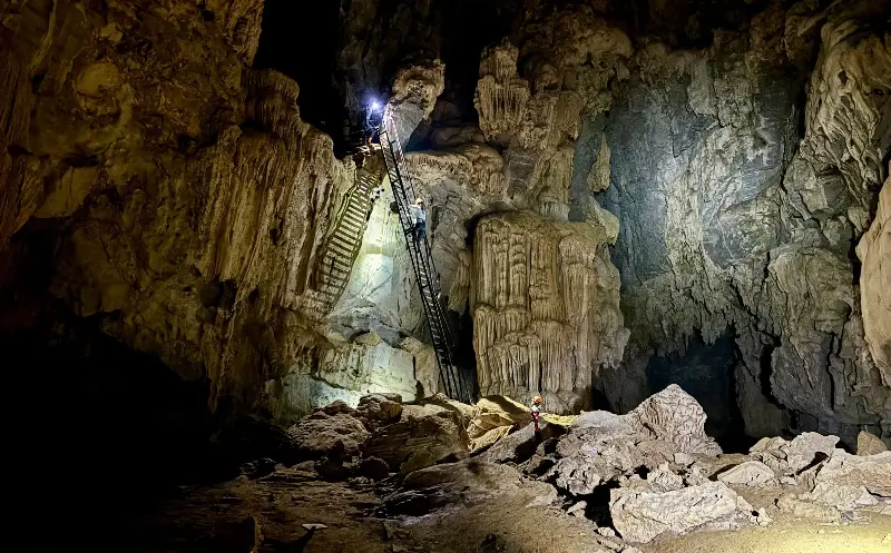 Visitors to Hung Ton cave wear harnesses to descend a steep ladder safely - Lee Cobaj