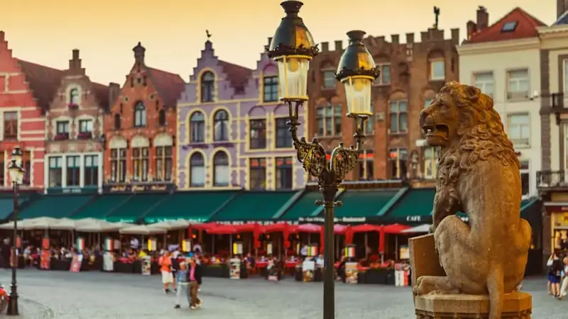 Traditional Belgian Lion Statue in front of City Hall and Colorful Brick Buildings in Market Square, Bruges, Belgium