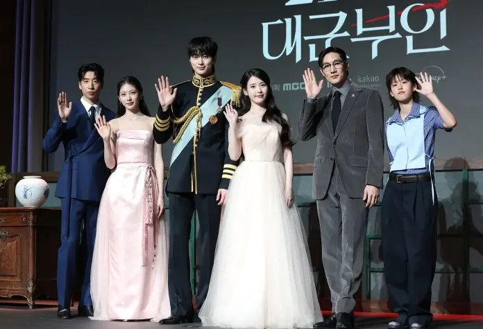Perfect Crown cast, dressed in formal and stylish outfits, standing together and waving at the camera during a promotional event.