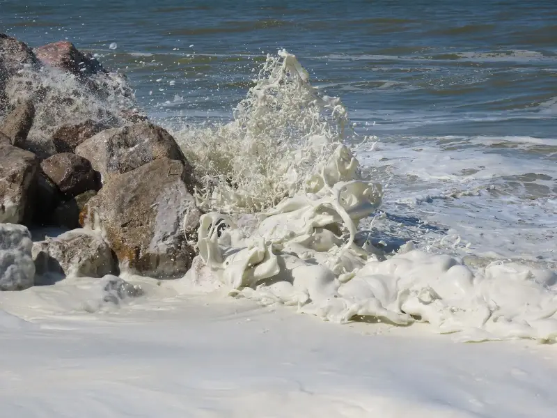 Ocean waves breaking against rocks, throwing up sea spray and foam.