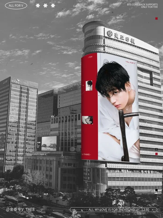 A large digital billboard in a cityscape featuring a promotional image for BTS member V, set against a backdrop of urban buildings and a cloudy sky.
