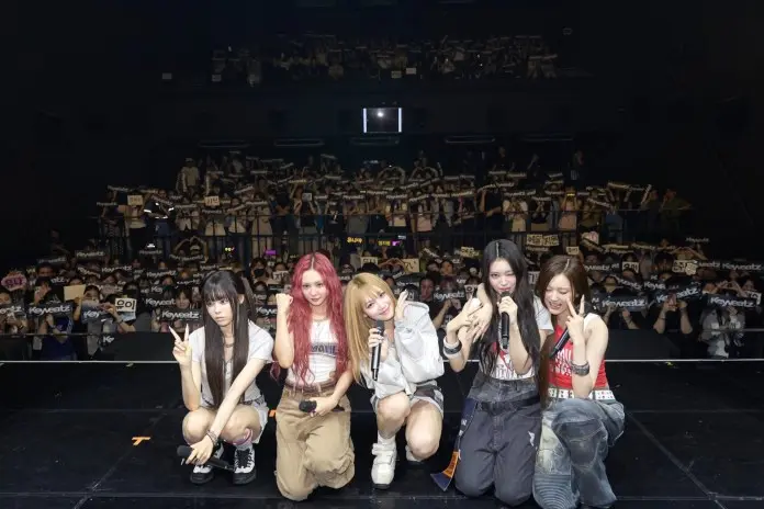 Keyveatz is posing on stage with fans holding banners in the background during a concert.