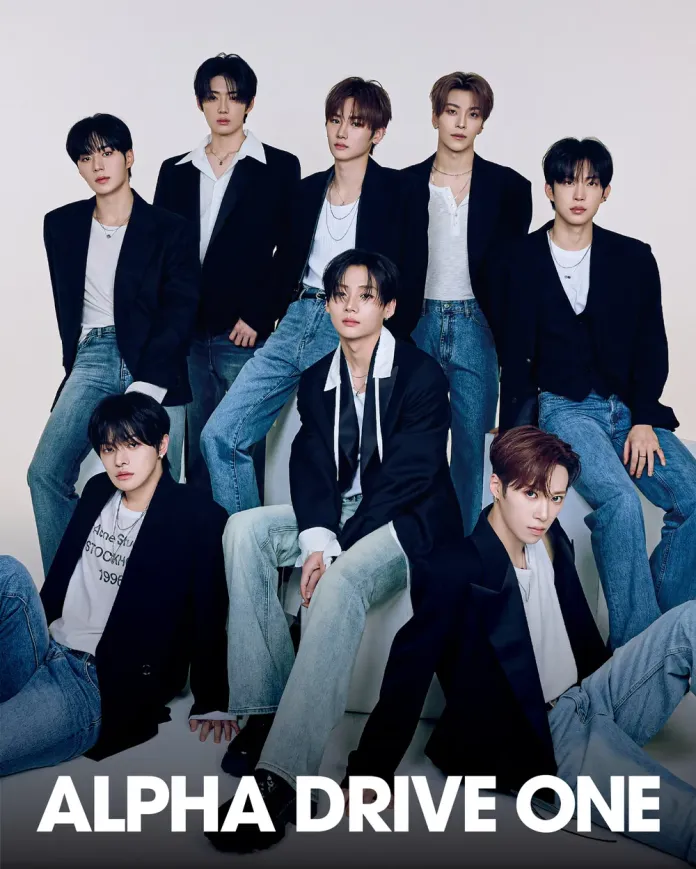 ALPHA DRIVE ONE posing together with a casual yet fashionable look, wearing blazers and denim. The foreground features one member seated, while the others stand behind.