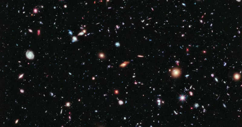 A deep Hubble exposure filled with thousands of faint, distant galaxies of many colors against black sky