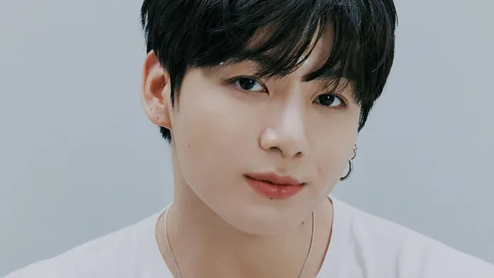BTS Jungkook with dark hair and earrings, looking directly at the camera with a neutral expression.