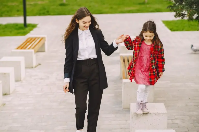 Fashionable mother with daughter. Family in a spring city. Woman in a black suit.
