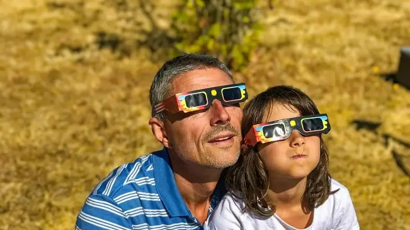 Father and daughter viewing solar eclipse with special glasses