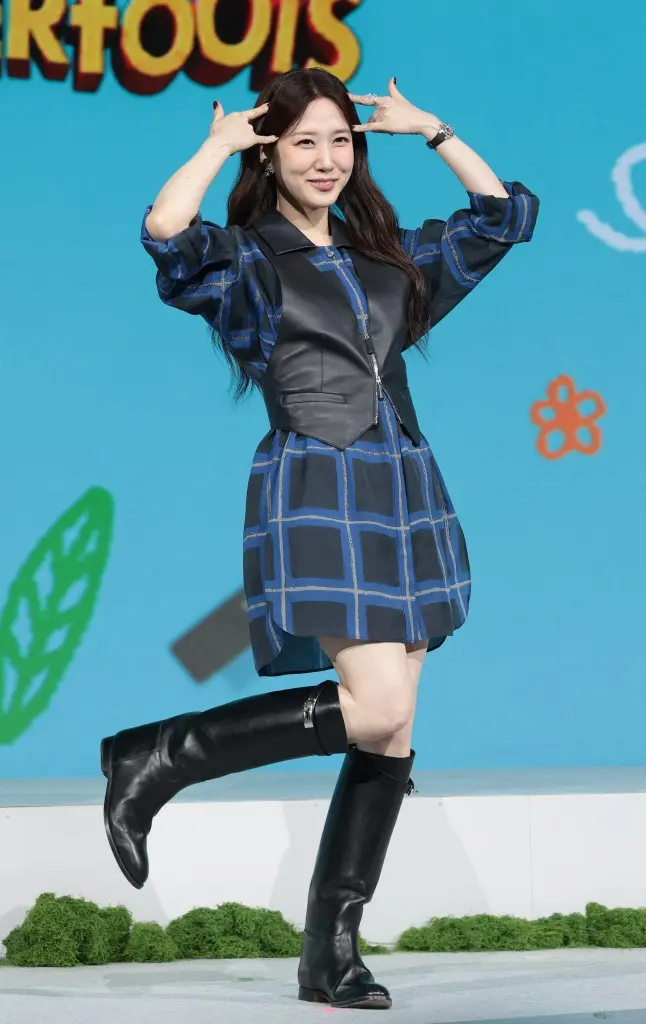 Park Eun-bin posing playfully with her hands on her head, wearing a blue patterned dress and black knee-high boots, on a stage with a colorful background.