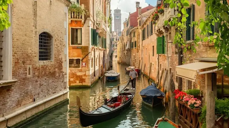 Canal through buildings on sunlit day in Venice, Italy