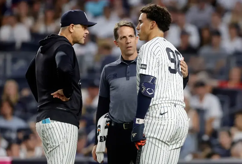George Lombard Jr. #96 of the New York Yankees (R) is checked on by manager Aaron Boone #17 (L) and trainer Tim Lentych (C) after a swing during his second inning at-bat against the Boston Red Sox in game two of the doubleheader at Yankee Stadium on August 29, 2026 in New York City. Lombard Jr. later left the game. (Photo by Jim McIsaac/Getty Images)