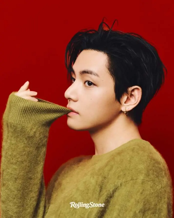 Profile portrait of BTS V with short dark hair wearing a green sweater, posed against a red background.