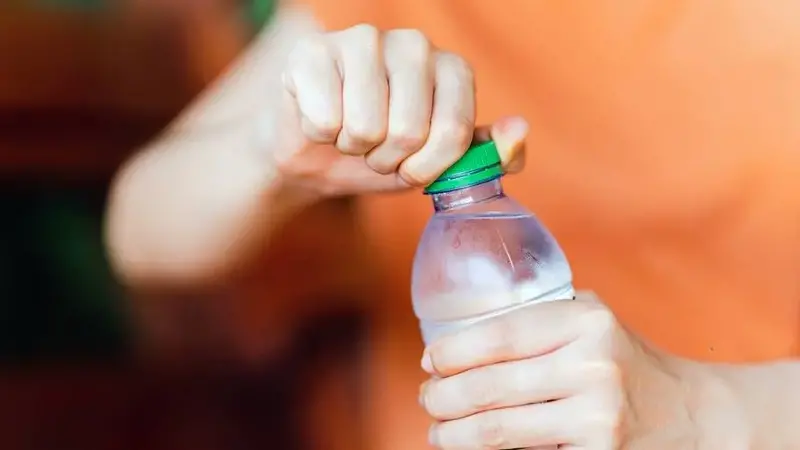 Person twisting cap off bottled water