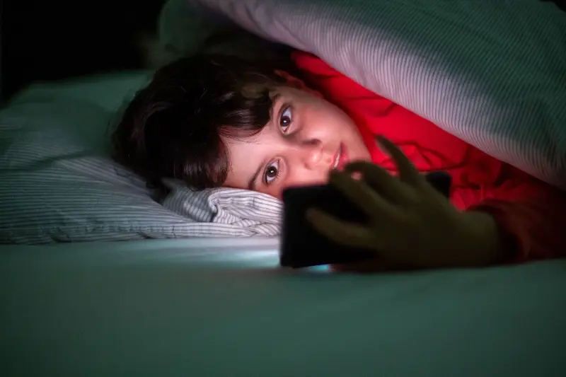 The health benefits of sleep are disrupted if a child keeps scrolling on their phone while in bed. 